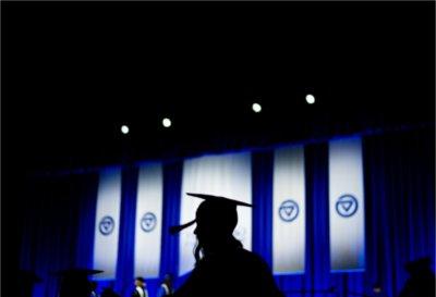 一个毕业生的剪影映衬在蓝白相间的横幅上.