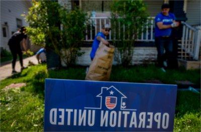 yard of home with porch in background, yard sign Operation United in blue in front